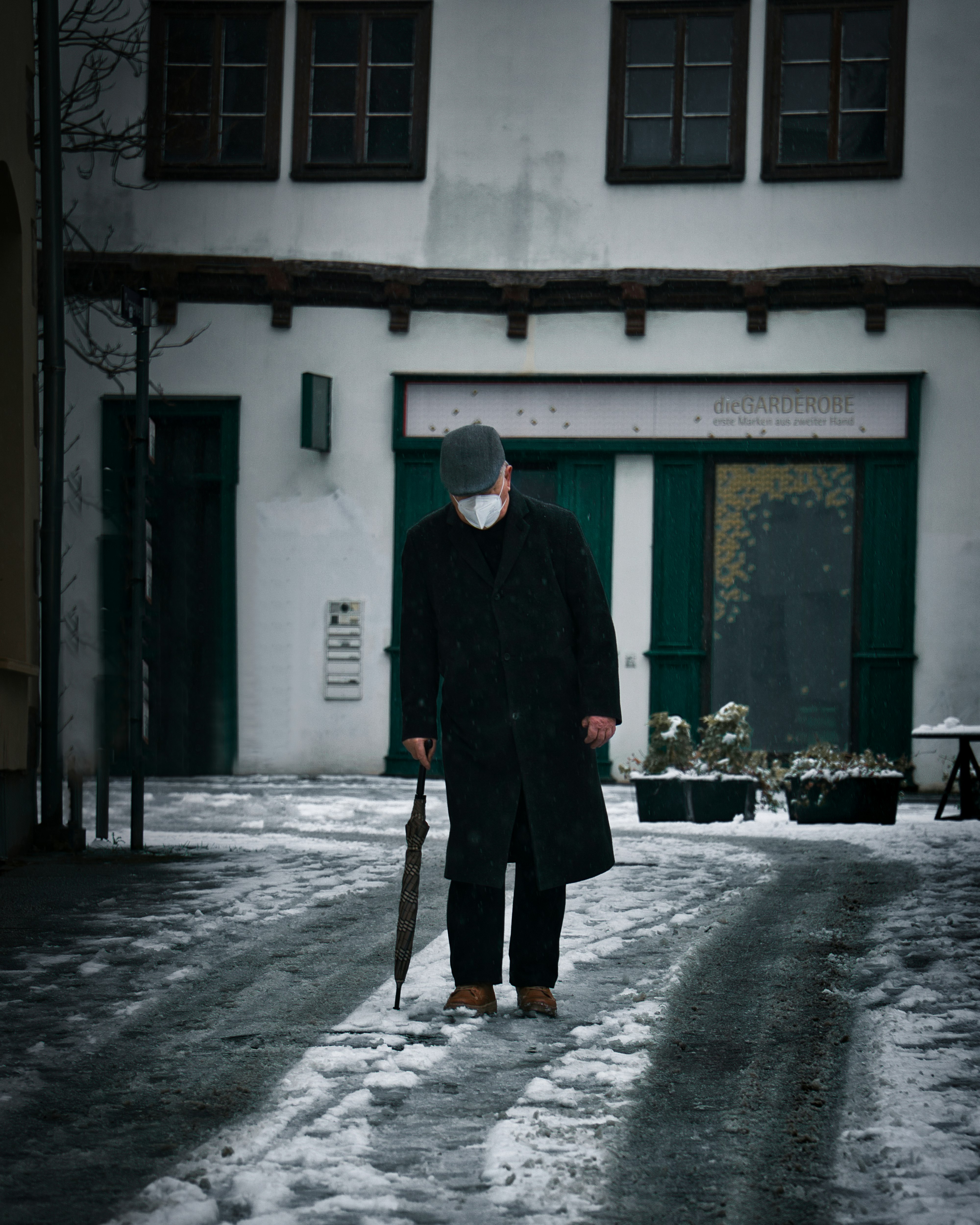 man in green coat standing in front of white concrete building